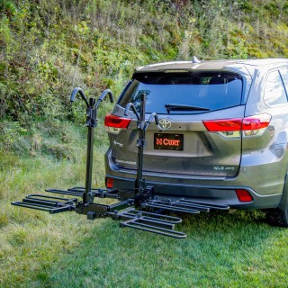 CURT Tray-Style Hitch-Mounted Bike Rack for Secure Transport CURT tray-style bike rack with hitch-mount, holding four bikes securely.