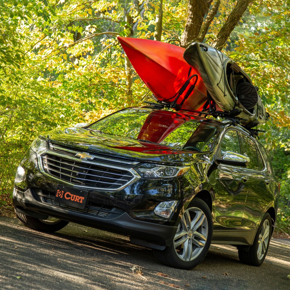 CURT kayak roof rack with adjustable arms and foam padding on vehicle roof