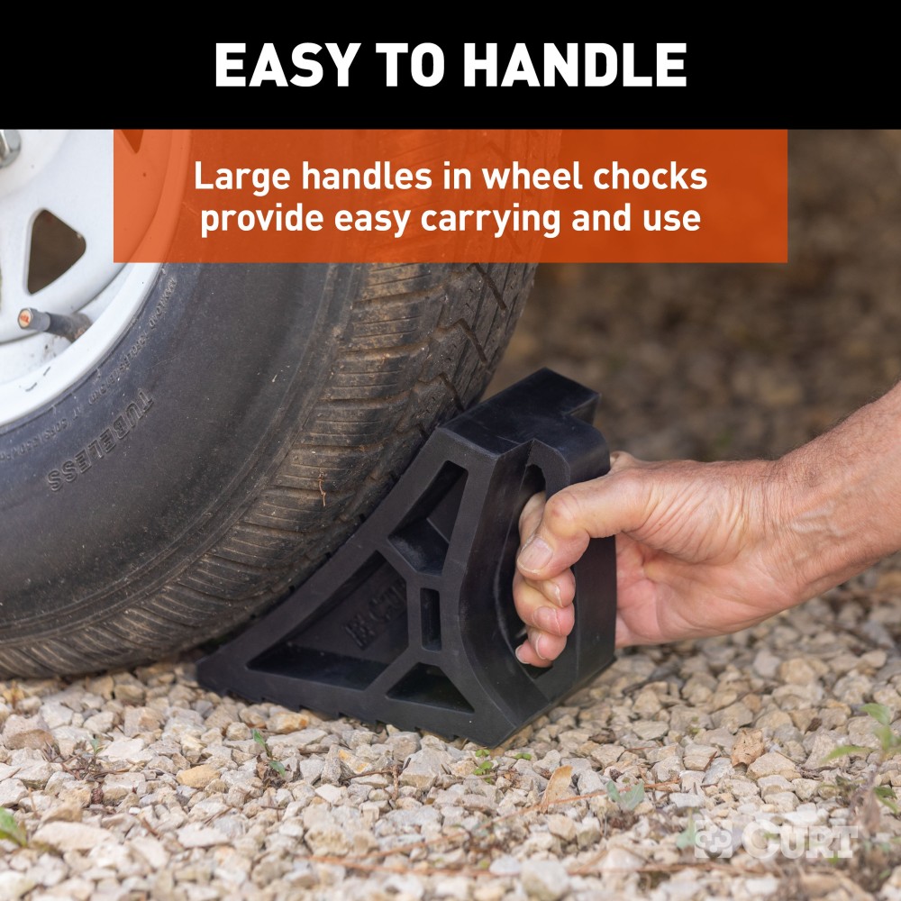 CURT HD Wheel Chocks with Mounting Bracket for Easy Storage CURT HD wheel chocks with mounting bracket attached to trailer, shown in use.