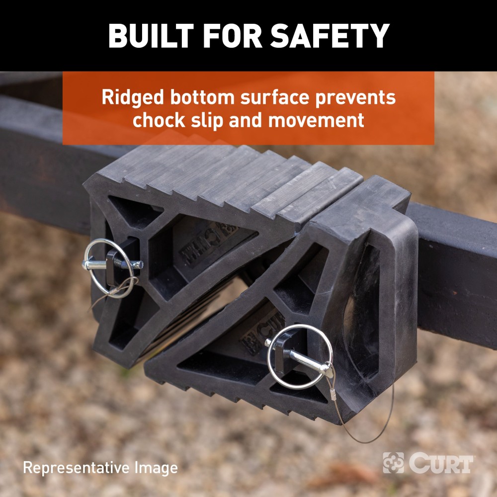 CURT HD Wheel Chocks with Mounting Bracket for Easy Storage CURT HD wheel chocks with mounting bracket attached to trailer, shown in use.