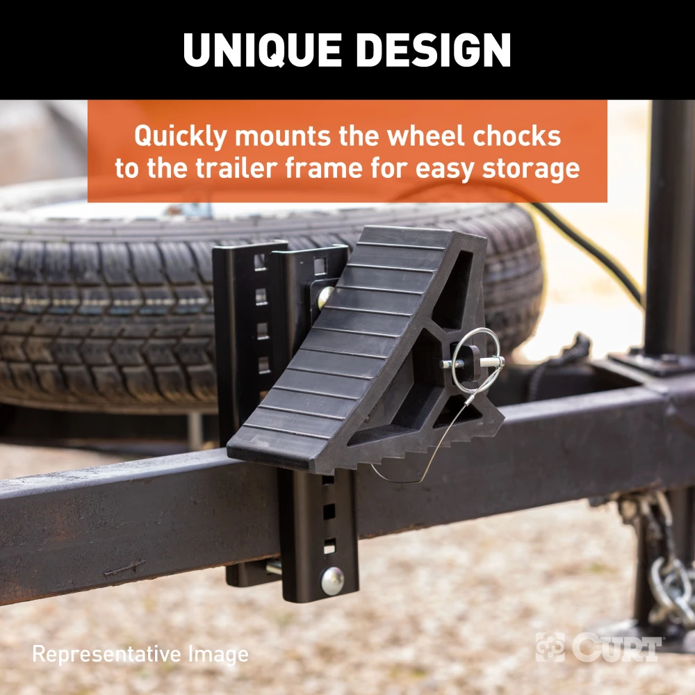 CURT HD wheel chocks with mounting bracket attached to trailer, shown in use.