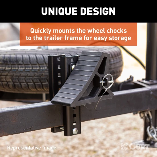 CURT HD wheel chocks with mounting bracket attached to trailer, shown in use.
